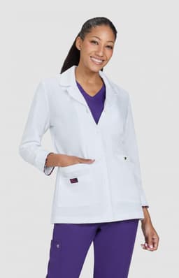 A white lab coat with a button front and pockets, worn over a purple top, modelled by a smiling woman.