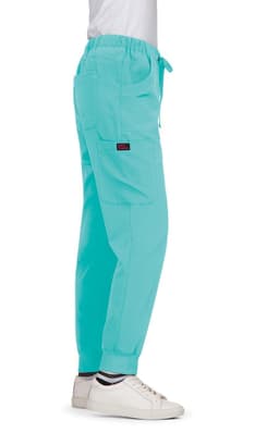 Turquoise Aster Pants displayed on a model, featuring a loose fit and cargo pockets. The model wears white shoes.