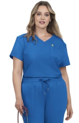 A woman wearing a blue scrub top with a pocket, featuring a logo on the left side.