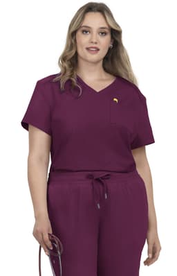 A woman wearing a short-sleeved, burgundy medical scrub top with a pocket and matching jogger-style pants.