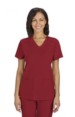 A red scrubs top with a V-neck design and two front pockets, worn by a smiling woman. The garment features a logo.