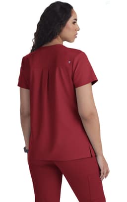 A red scrubs top featuring a back pleat design, short sleeves, and a logo.
