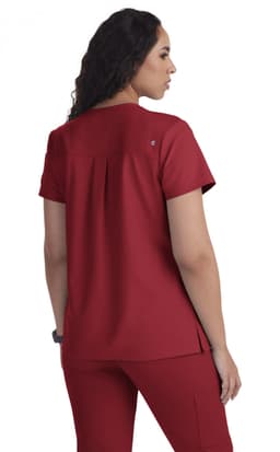 A red hospital scrub top with a pleat detail at the back. The garment features a small logo.