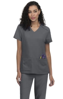 A grey scrub top featuring a V-neck design and two front pockets. The model has curly hair and stands confidently.