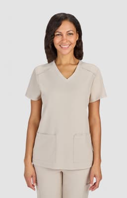 A beige medical scrub top with a V-neckline and two front pockets, worn by a smiling woman.