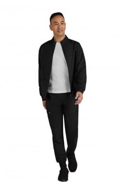 A black men's jacket is worn over a grey top, paired with matching black pants and shoes. The model is walking.