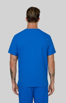 A man wearing a blue scrub top, viewed from behind, with matching blue scrub pants. The outfit includes a logo.
