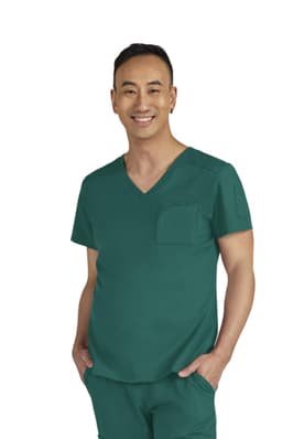 A man in a teal medical scrub top with a pocket, smiling against a neutral background. The outfit has branding details.