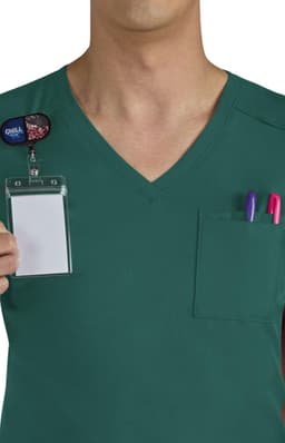 A green scrub top with a pocket containing pens and a blank name badge. The shirt features a V-neck design.