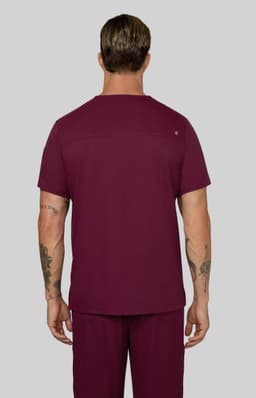 A man wearing a short-sleeved maroon shirt, viewed from the back, with tattoos visible on his arms.