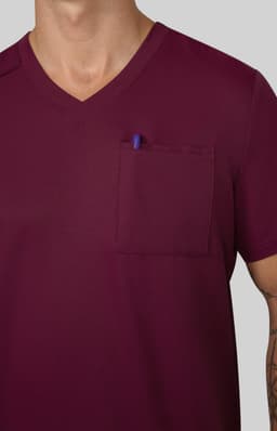 A burgundy V-neck shirt featuring a chest pocket with a pen inserted. The fabric appears smooth and solid.