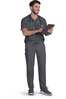 A person wearing grey scrubs and a stethoscope, standing while holding a tablet. The outfit includes pockets and a logo.