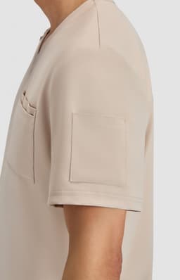 A short-sleeved beige top featuring a pocket and a patch pocket on the sleeve, with a smooth fabric finish.