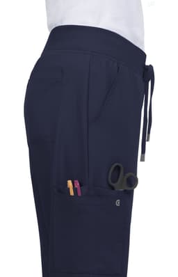 Atria Pant in navy blue, featuring side pockets with scissors and pens visible, and a drawstring waistband.
