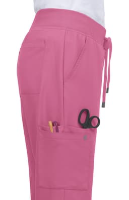 Atria Pant in bright pink with pockets containing pens and scissors, showcasing a side view.