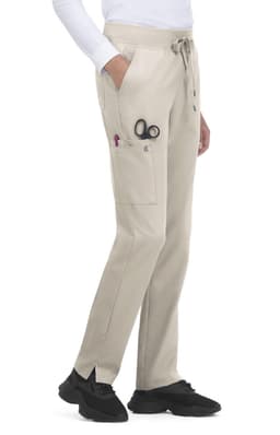Atria Pant in light beige, featuring pockets and a drawstring waist. Includes scissors and pens in the side pockets.