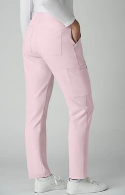 Atria Pant in pink featuring a fitted style and side pockets. The model is wearing white shoes.