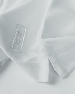 A white polo shirt featuring a logo, displayed with a focus on the fabric and collar details.