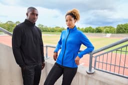 A promotional image featuring a black and a blue men's structured fleece jacket displayed on models at a sports venue.