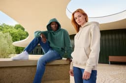 A khaki oversized hoody on a person and a green oversized hoody on another person, both in an outdoor setting.
