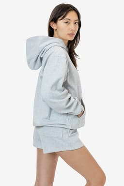A light grey heavy fleece hood pullover displayed on a model, featuring a hood and a relaxed fit.