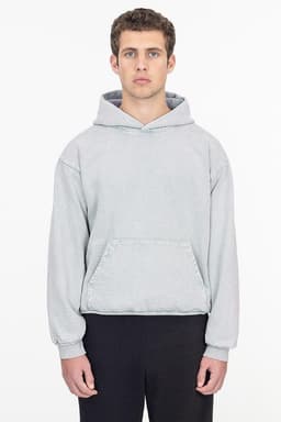 A grey mineral wash heavy fleece hooded pullover with a front pocket. The model stands with a neutral expression.