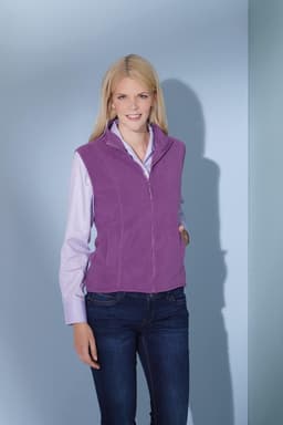 A purple microfleece vest worn over a light pink shirt, paired with dark jeans. The model has long blonde hair.