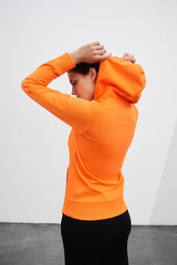 A bright orange ladies hooded sweatshirt with a fitted design, featuring a hood and a sleek silhouette.