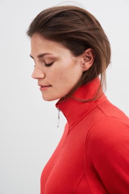A women's red jacket with a high collar and a zip detail, featuring a sleek, fitted silhouette.