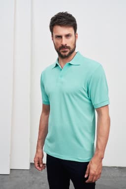 A mint green polo shirt featuring a collar and short sleeves, modelled by a man against a neutral background.