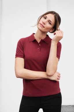 A burgundy polo shirt for women, featuring a collar and short sleeves, with a subtle logo.