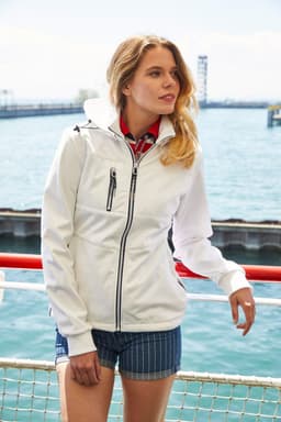 A white maritime jacket with a hood, featuring a zip closure and a pocket, worn by a model by the water.