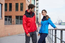 A red and black men's all-weather jacket and a blue women's jacket, both designed for rain protection, displayed by models.