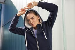A navy blue ladies doubleface jacket features a hood and contrasting inner lining, with a model posing outdoors.