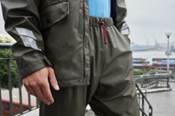 Worker rain pants in olive green, featuring an elastic waistband with a drawstring and reflective stripes.
