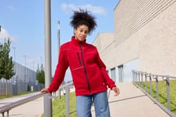 A red fleece jacket with a corduroy look, featuring a branded logo, worn by a model outdoors.