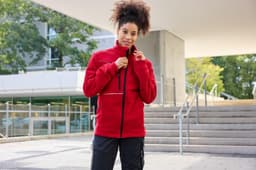 A red fleece jacket with a corduroy look, featuring a zippered front and a stylish collar. It has a logo.