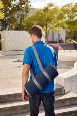 A picnic blanket in a navy blue carry bag is slung over the shoulder of a person wearing a blue shirt.
