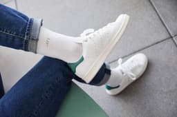 Function Sport Socks in white feature a logo, paired with white sneakers and denim jeans.