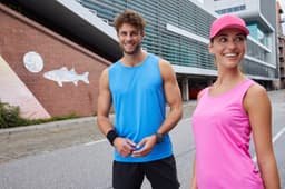A blue active tank top on a man and a pink active tank top on a woman, both posing outdoors.