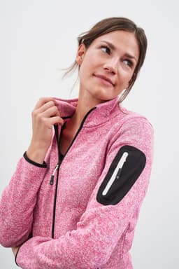 A pink knitted fleece jacket featuring a zip and a black accent on the sleeve, worn by a woman.