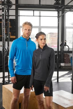 A blue half-zip sports shirt and a black half-zip sports shirt displayed on individuals in a gym setting, featuring logos.