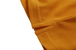 A close-up of an orange polo shirt fabric, highlighting stitching details and texture. The shirt features a logo.