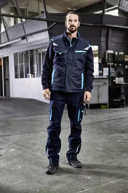 A padded work vest in navy blue with light blue accents, featuring pockets and a logo, worn by a person indoors.