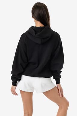 A black mineral wash fleece wide hoodie with a hood, worn with white shorts, showcasing a relaxed fit.