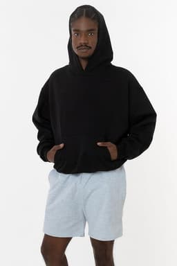 A model wearing a black mineral wash fleece wide hoodie paired with light grey shorts, featuring a logo.