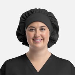 A black bouffant cap worn by a smiling person in a black top. The cap features a gathered design and a smooth band.