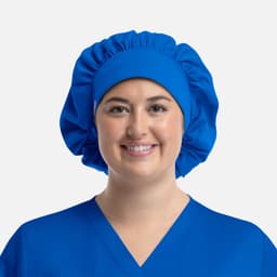 A blue bouffant cap worn by a smiling person, featuring a gathered design for a secure fit.