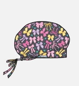 A printed unisex bouffant cap featuring a dark background with a pattern of colourful bows in pink, yellow, and purple.