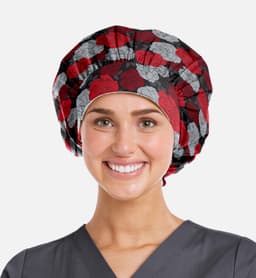 A printed unisex bouffant cap featuring a floral pattern in red and grey, worn by a smiling person in scrubs.